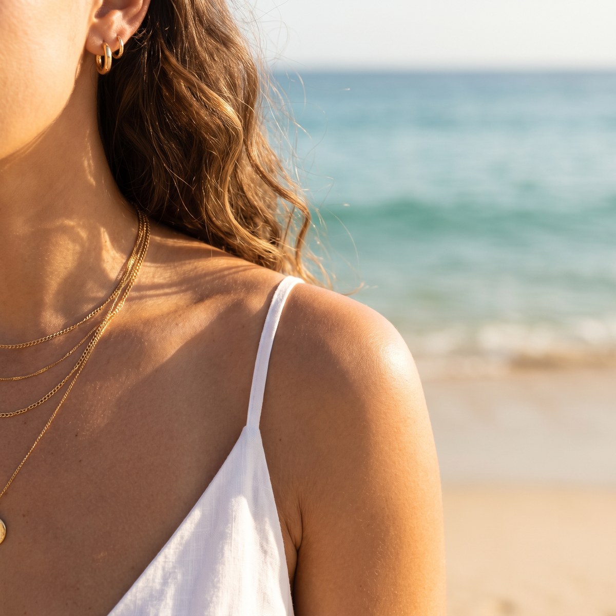 Layered gold necklaces on sun-kissed skin